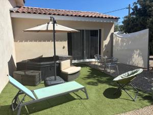 a patio with a chair and an umbrella and a couch at Au Petit Bueix in Sillans-la Cascade