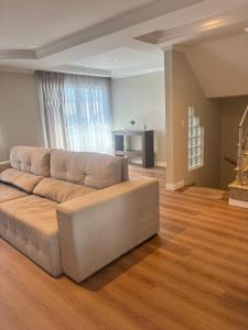 a living room with a large couch in front of a window at Sobrado in Curitiba