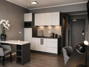 a kitchen with white cabinets and a table and chairs at THE ROOMS - Hotel & House in Frankfurt