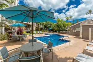 a table with an umbrella next to a swimming pool at Grand Champions 185 in Wailea