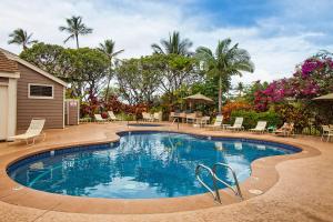 a swimming pool with chairs and trees and a house at Grand Champions 185 in Wailea