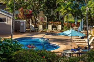 a swimming pool with a table and an umbrella at Grand Champions 185 in Wailea