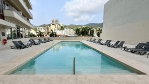 a swimming pool with chairs and a building at Holiday Inn Acapulco Amarea by IHG in Acapulco