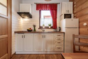 a kitchen with white cabinets and a white refrigerator at DW KINGA Domki całoroczne 6 os z widokiem na Tatry in Kacwin