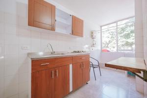 eine Küche mit Holzschränken, Spüle und Tisch in der Unterkunft Apartamento Edificio Neon Centro in Ibagué
