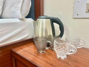 a tea kettle and glasses on a table next to a bed at Land Chaster Kasauli in Kasauli +18 photos
