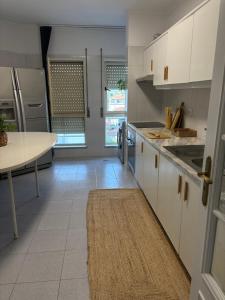 a kitchen with white cabinets and a table in it at T2 central Valença in Valença