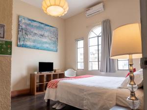 a bedroom with a bed with a lamp and a tv at Barrio Antiguo Hostel HK in Monterrey