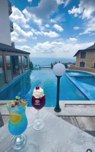 two drinks on a table next to a swimming pool at Aurora Kopaonik in Raška