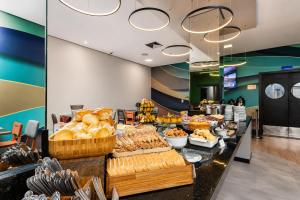 a buffet line with different types of bread and pastries at Comfort Hotel Joinville in Joinville