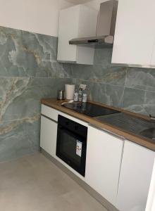 a kitchen with white cabinets and a black microwave at Sorrento Gem House in Meta
