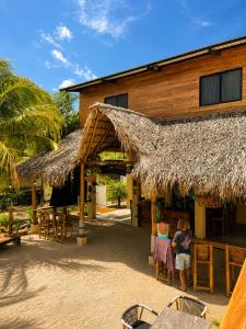 two people standing in front of a building with a straw roof at Tipsy Gypsy Bar & Hotel in Tola