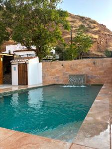 a swimming pool with a waterfall and a stone wall at Cuevas Uropia in Graena
