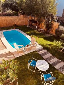 a backyard with a swimming pool with chairs and a table at Las Pircas Apartamentos - Centro de Cafayate in Cafayate
