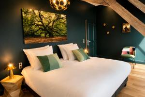 a bedroom with a large white bed with a painting on the wall at La Villa Du Temple - Climatisation in Auxerre