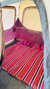 a tent with a striped blanket on the ground at Seravelle Adventure Camping in Kitulgala