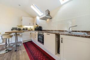 a kitchen with white cabinets and a red rug on the floor at The Retreat with Free Parking in Ambleside +11 photos