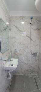 a white bathroom with a sink and a shower at Vila Nakaj Guest House in Gjirokastër +37 photos