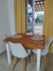 a wooden table with white chairs and a window at Refugio del viajero in Chajarí