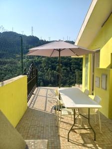 a table and chairs with an umbrella on a balcony at Poço Cávado House T3 in Geres