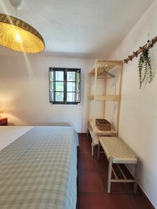 a bedroom with a bed and a bench and a window at Casa da Água Formosa in Vila de Rei