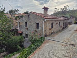 an old stone house on the side of a road at Casa da Água Formosa in Vila de Rei