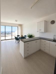 a kitchen with white cabinets and a table and chairs at Oroklini Hills Modern Sea View Apartments in Oroklini