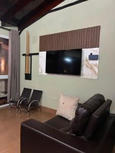 a living room with a black leather couch and chairs at Casa Bioma da Chapada in Chapada dos Guimarães