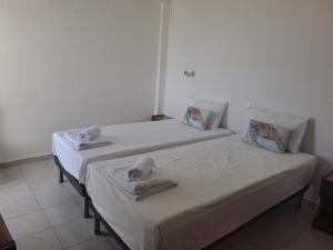 two beds in a room with towels on them at Annabel Apartments in Theologos