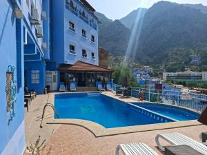 a hotel with a swimming pool in front of a building at Maison d'hôte Bousaid in Chefchaouen