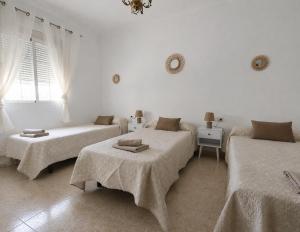 a white room with three beds and a window at Casa Paco & Carmela in Algodonales +24 photos