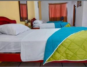 two beds in a hotel room withacers at Hostal Jireh in Manta +10 photos