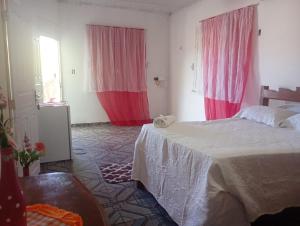 a bedroom with two beds and pink curtains at Pousada kurasi alter 02 in Santarém