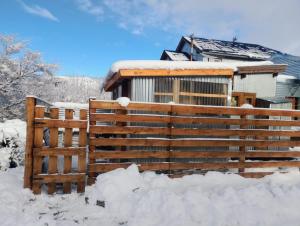 a house with a wooden fence in the snow at Casa Nido Tiny House in El Chalten