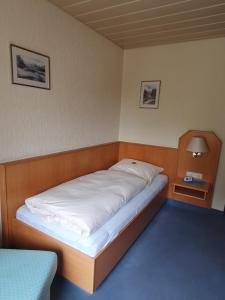 a bed in a small room with a white blanket at Hotel Gasthaus zur Krone in Gochsheim