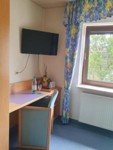 a room with a desk and a window with a television at Hotel Gasthaus zur Krone in Gochsheim