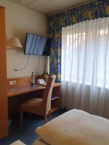 a desk in a hotel room with a bed and a television at Hotel Gasthaus zur Krone in Gochsheim
