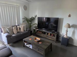 a living room with a couch and a flat screen tv at Private Room with Queen Bed & Bathroom in Bellbird Park