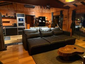 a living room with a leather couch and a table at Cabana Refúgio da Montanha in Alfredo Wagner