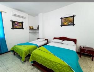 a bedroom with two beds with green and blue sheets at Hostal Jireh in Manta
