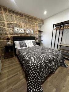 a bedroom with a black and white bed and a brick wall at Caneliña in Ourense