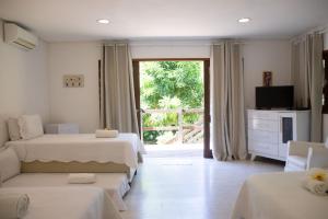 a bedroom with two beds and a tv and a window at Suites Amma Noronha in Fernando de Noronha
