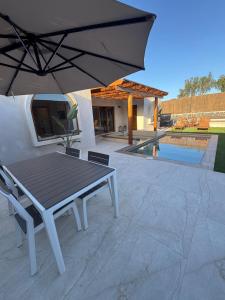 a table and chairs with an umbrella on a patio at Villa Majora - Piscina climatizada in Tuineje