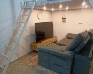 a living room with a blue couch and a ladder at Estúdio 800m do Buriti Shopping in Aparecida de Goiânia