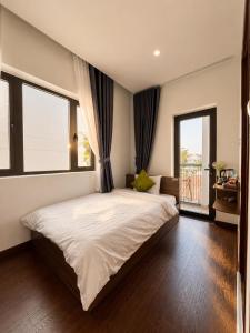 a bedroom with a large bed and two windows at Saffron Boutique Hotel in Da Lat