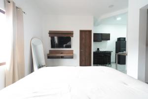 a bedroom with a white bed and a kitchen at La Palma Experience in Panama City