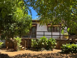 a house with a fence and trees in front of it at Suites Amma Noronha in Fernando de Noronha