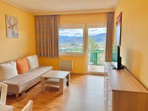 a living room with a couch and a large window at Apartment Karawankenblick with Lake View - Free Parking in Pörtschach am Wörthersee