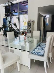 a glass table and white chairs in a room at Trade winds International in Progreso