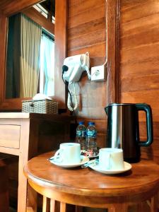 a wooden table with two cups and a tea kettle at Double'D Hostel in Nusa Penida